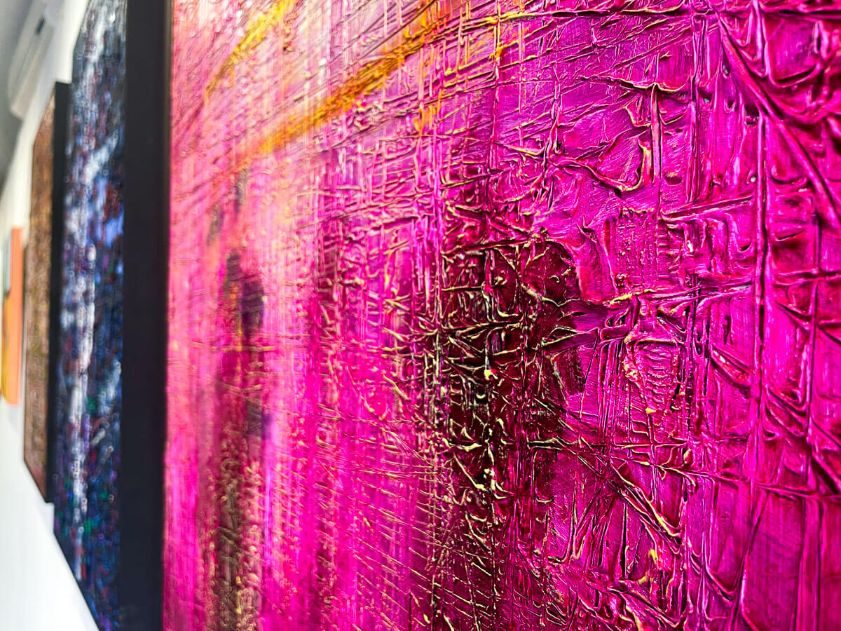Detail of an abstract painting by James de Villiers. The painting is brigh pink with lots of texture in a grid pattern.